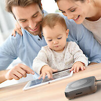 Eine Mutter, ein Vater und ein Kind sehen sich Fotos an, die auf einem Gerät von Amber gespeichert sind.