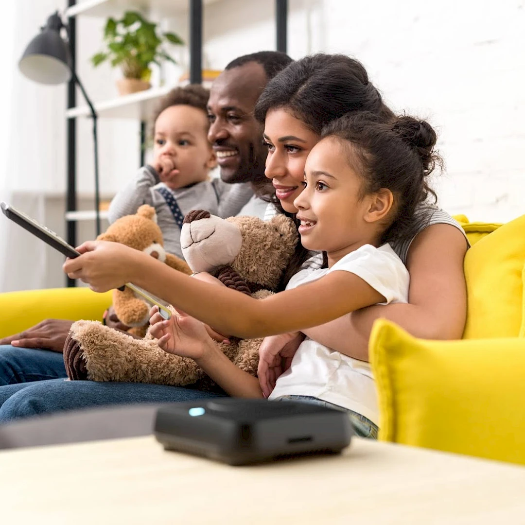 Una famiglia che guarda foto e video su un televisore con un dispositivo Amber X in primo piano.