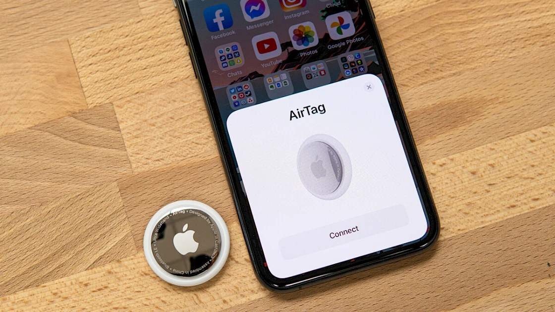 Apple AirTag on a desk next to an iPhone