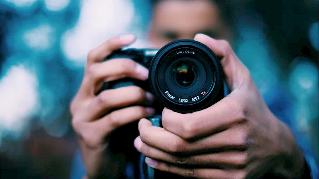 Closeup of camera lens with man behind the camera