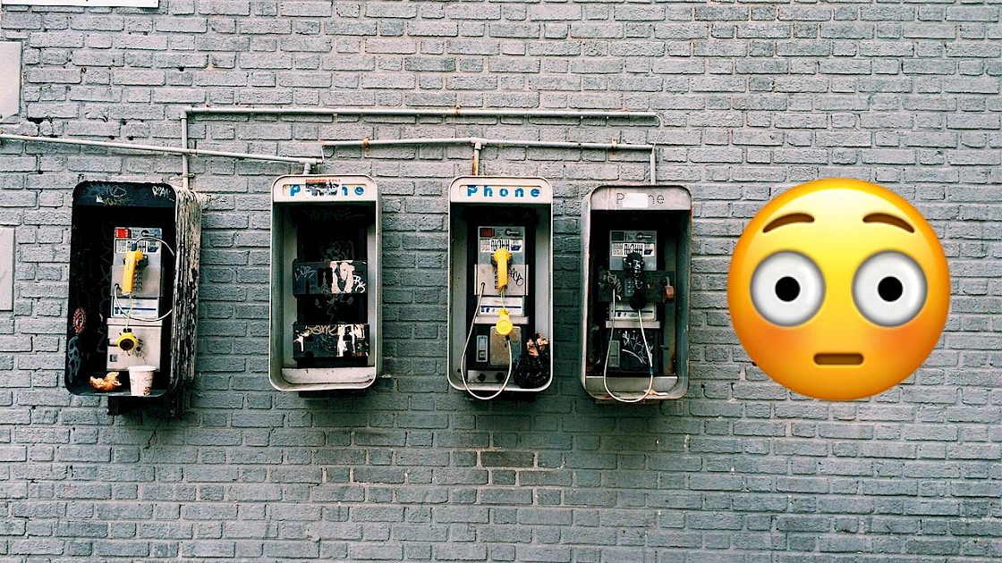 Surprised Emoji next to 4 payphones on a brick wall