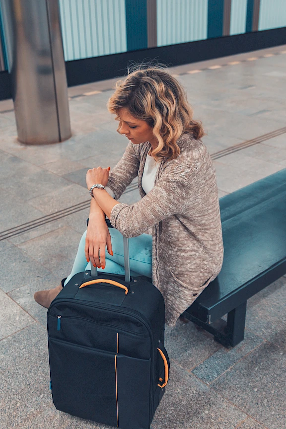 A woman sits beside her bag in an airport